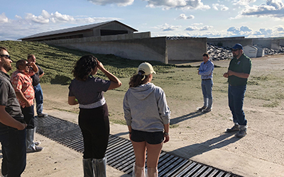 staff talking to a crowd with large buildings in the background