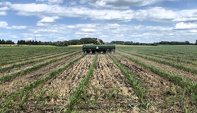 A field with short corn stalks and machinery planting in between the rows.