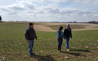 Three people standing in a farm field