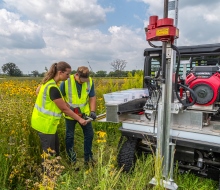 two people using a soil probe to collect samples that will be tested for carbon