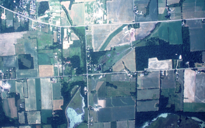 Aerial view of rural land with cropland, woodland, lakes, roads, houses visible